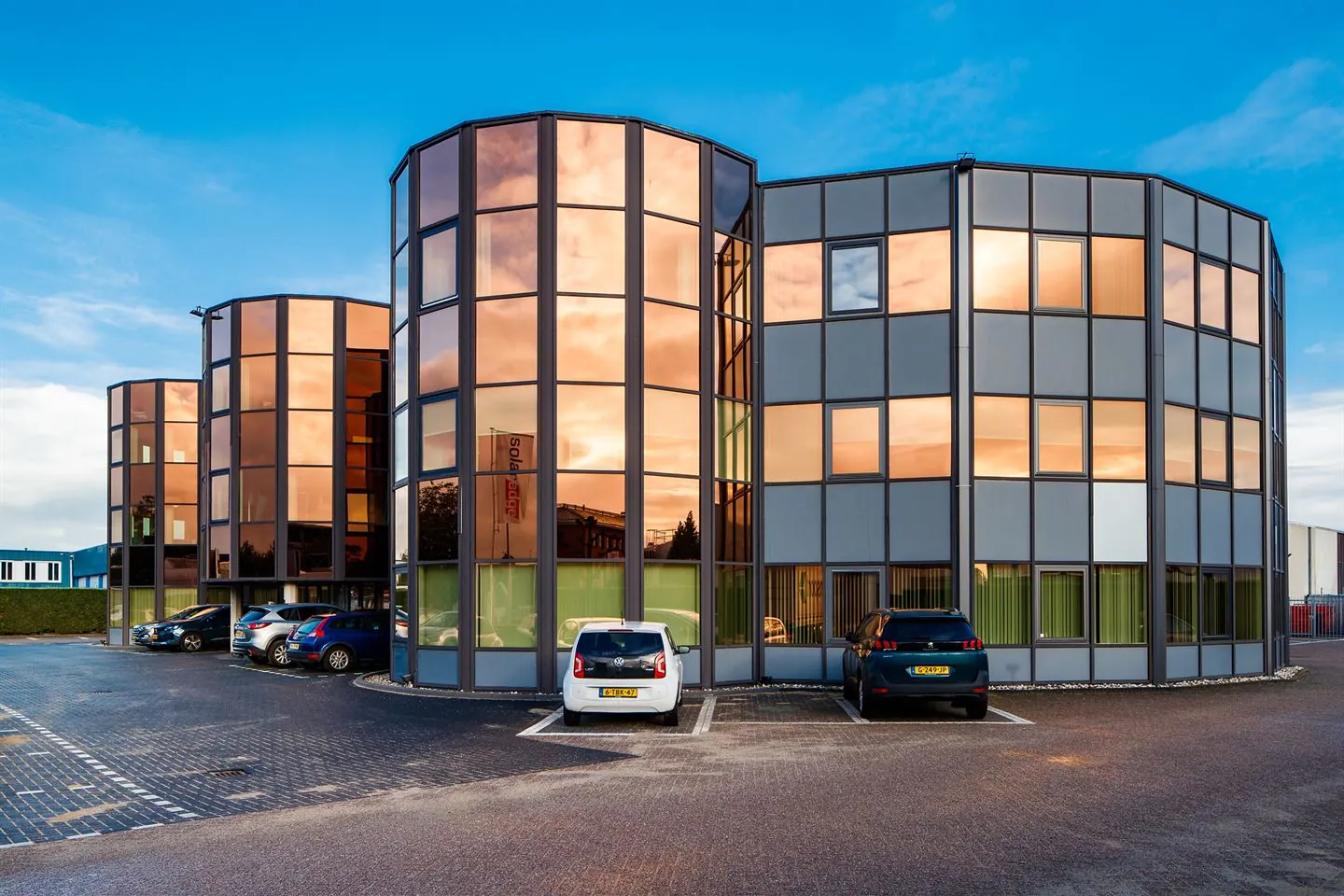 Modern kantoorgebouw aan de Lange Dreef met spiegelende gevel en geparkeerde auto's op de voorgrond.